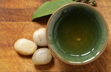Glass of green tea with some polished pebbles.